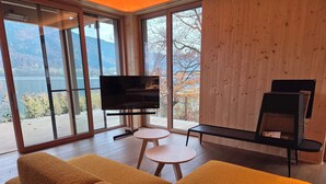 A modern living room with a large TV, two round tables, and a sofa. - Seezeit am Ossiacher See (Bodensdorf)