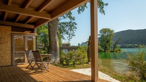 A wooden deck with two chairs and a table, overlooking a lake and hills. - Seezeit am Ossiacher See (Bodensdorf)