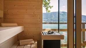 A wooden cabin with a sauna, a view of a lake, and a mountain in the background. - Seezeit am Ossiacher See (Bodensdorf)