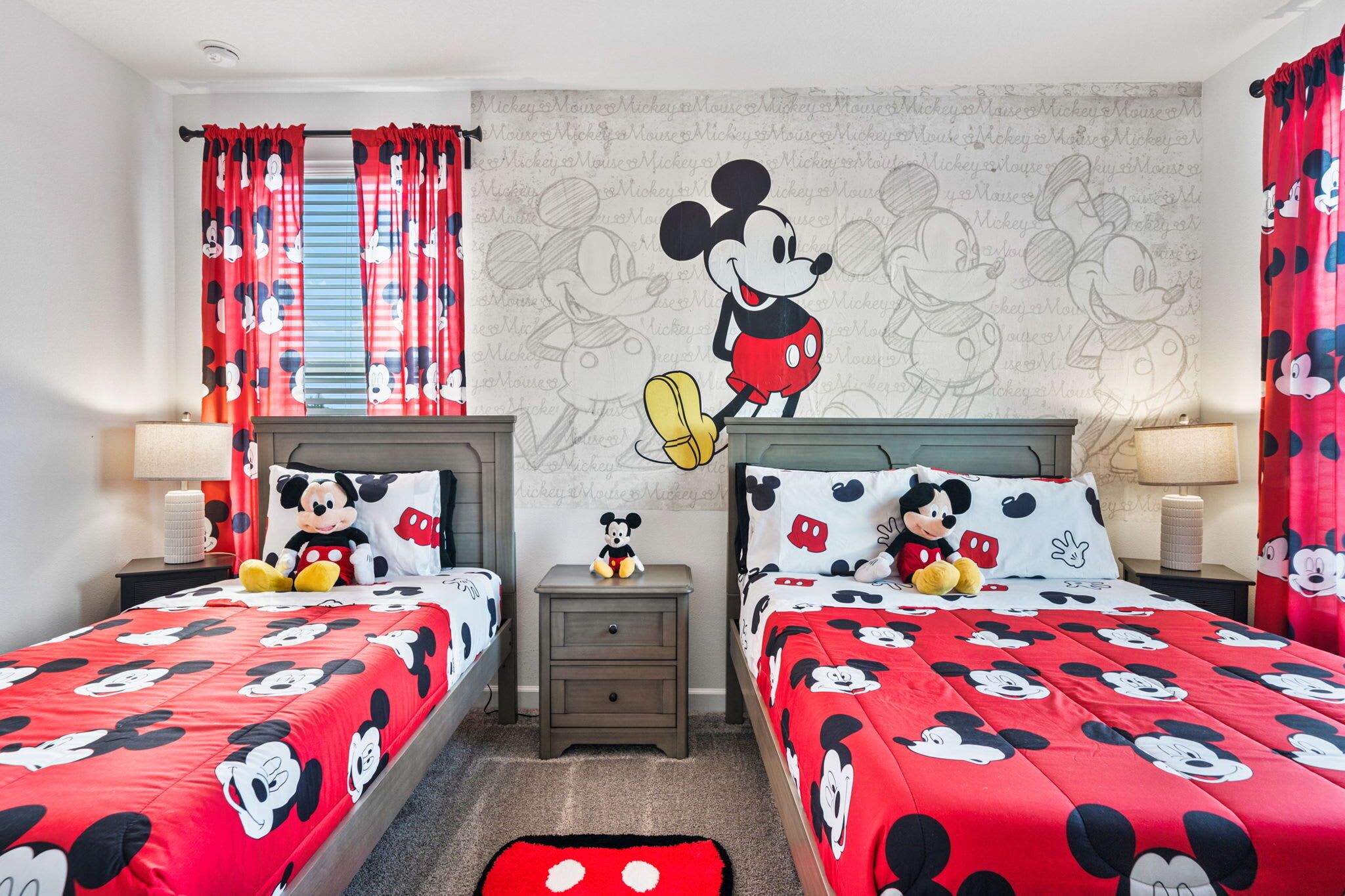 Een kamer met twee bedden, elk met Mickey Mouse beddengoed, een Mickey Mouse muurstickers en passend bedtextiel.