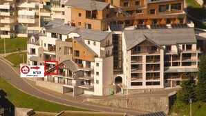 Un edificio residencial moderno con varios balcones, una escalera destacada e instalación de paneles solares.