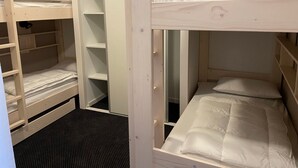 Cama litera con armario empotrado debajo, que incluye varias estanterías y una barra para colgar.