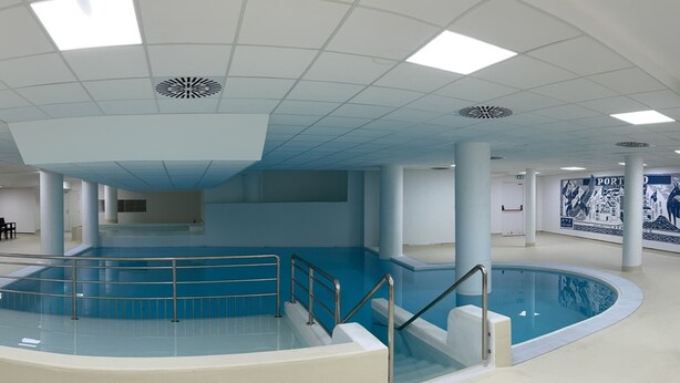 Una piscina interna con una scala centrale e un affresco sulla parete.