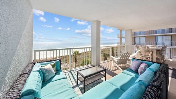 A balcony with a view of the ocean, furnished with a sofa, chairs, and a table. - Summer House 406B (Orange Beach)