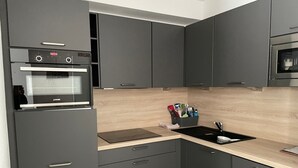 A modern kitchen with grey cabinets, a built-in oven, a sink, and a wooden countertop. - Gourette: Apartment 6 ppl, 57m², Pets allowed, Pool (Gourette)