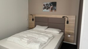 A neatly made bed with a white duvet, a wooden headboard, and a wall-mounted artwork above it. - Gourette: Apartment 6 ppl, 57m², Pets allowed, Pool (Gourette)