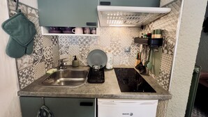 Een kleine keuken met een vaatwasser, een spoelbak, een kookplaat en een klein aanrecht.