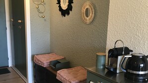 Een kitchenette met een koffiezetapparaat, een magnetron en een kleine koelkast. Er zijn twee zithoeken met dekens.