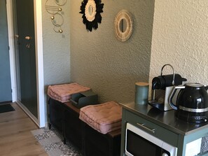 A kitchenette with a coffee maker, a microwave, and a small refrigerator. There are two cushioned seating areas with blankets. - Renovated cozy studio with south balcony - 2 pers. (Arâches-la-Frasse)