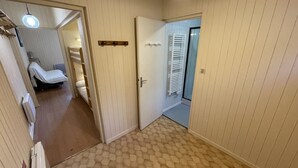 A hallway with a patterned floor, a door leading to a room with a bed and a radiator, and a ceiling light. - Spacious T2 with balcony near slopes in Le Lioran (Le Lioran)