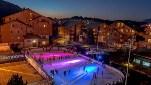 Een skigebied met een verlichte ijsbaan, omgeven door gebouwen.