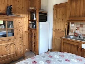 Eine Holzküche mit Kühlschrank, Mikrowelle und Spüle inklusive Geschirrgestell.