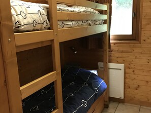 Ein Schlafsaal mit Etagenbetten, einem Fenster, Holzwänden und einer Heizung.