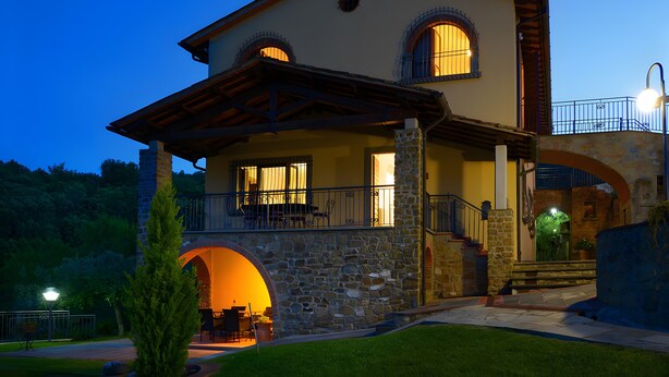A two-story building with a stone facade, a balcony, and an arched entrance. - Room 'Il Leccio - Podere Del Griccia' with Shared Pool, Wi-Fi and Air Conditioning (Civitella in Val di Chiana)