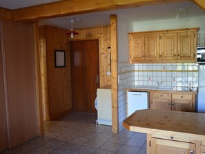 A kitchen with wooden cabinets, a tiled backsplash, a sink, and a refrigerator. - Charming 2-room with WIFI for 4 guests at Le Pernant (Arâches-la-Frasse)