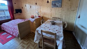 Une pièce chaleureuse avec un lit, une table sur laquelle se trouve un panier, une chaise et un mur en bois orné de décorations.