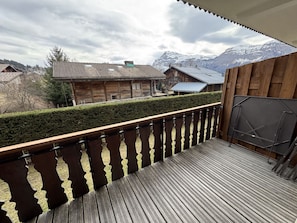 Ein Holzbalkon mit Blick auf ein Gebirge und traditionelle Gebäude.