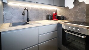 Una cocina moderna con estufa de acero inoxidable, un lavamanos y una cafetera.