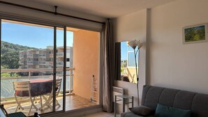 A balcony with a table and chairs, a sofa, and a lamp. - Studio with terrace in Bormes-les-Mimosas (Bormes-les-Mimosas)