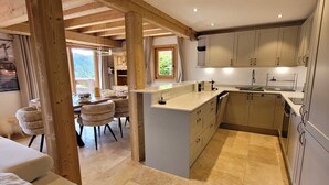 Una cucina moderna con travi in legno, una zona pranzo con sedie e vista sull'esterno.