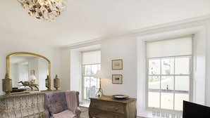 A room with a large mirror, a purple armchair, a wooden dresser, and a television. - Tri Raglan Bach (Beaumaris)