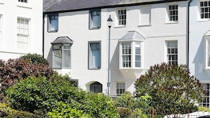 A row of white buildings with multiple windows and a street lamp. - Tri Raglan Mawr (Beaumaris)