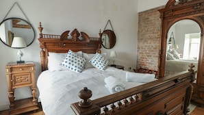 A wooden bed with a headboard, two bedside tables, and a large mirror. - Tri Raglan Mawr (Beaumaris)