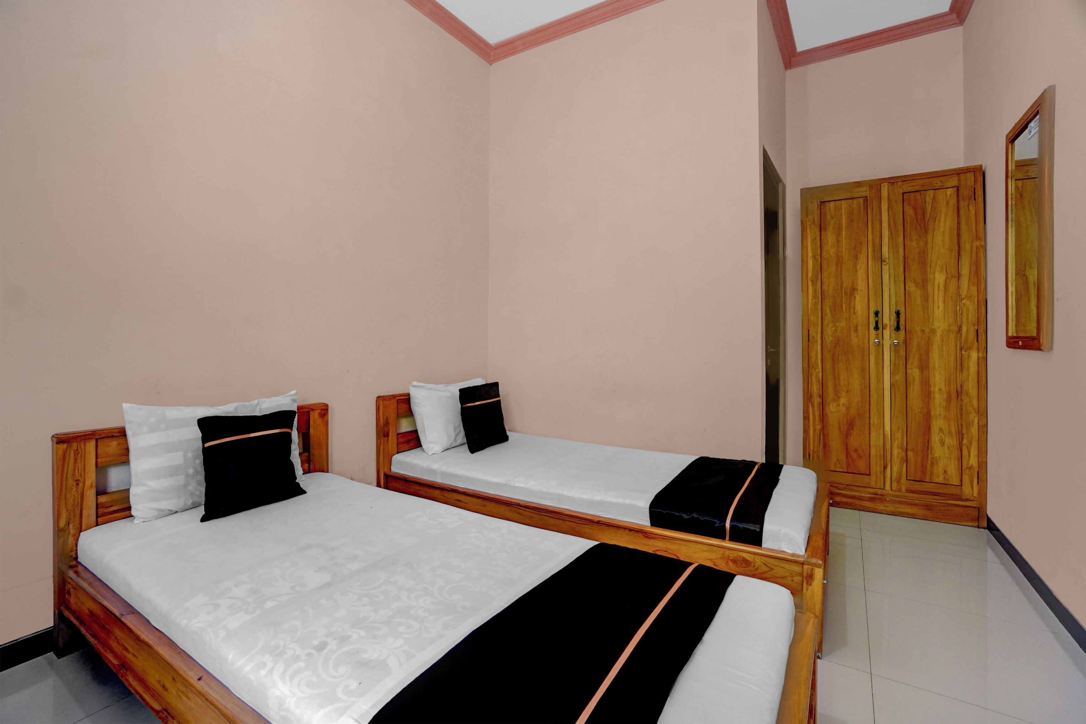 A bedroom with two wooden beds, a wardrobe, and a mirror.