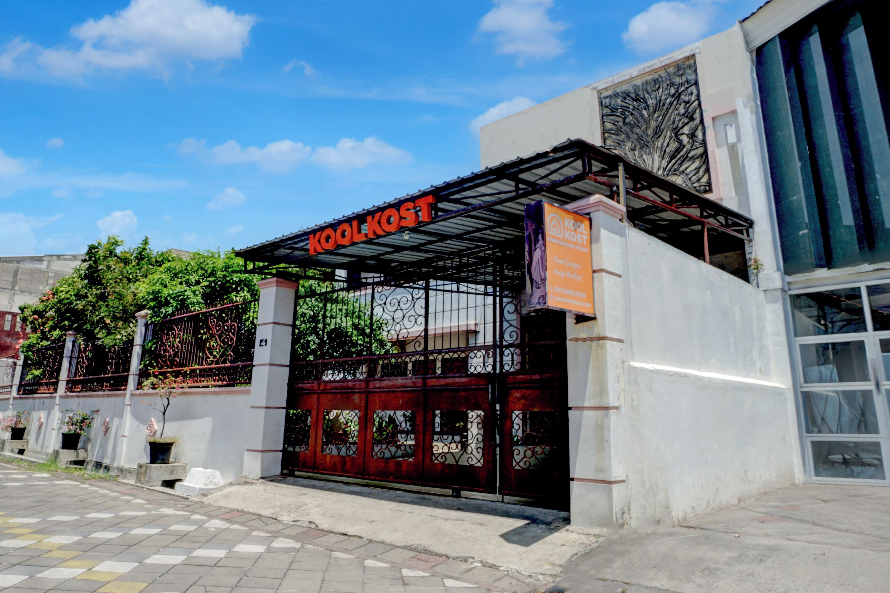 Un edificio con un cartel que dice "Koolkost" y una entrada con portón.