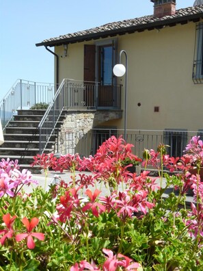 Un edificio con una scala che conduce a un balcone, circondato da fiori rosa.