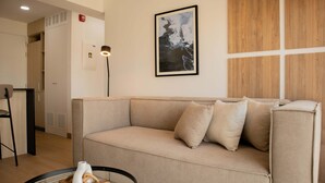 A modern living room with a beige sofa, a framed abstract painting, and a glass coffee table. - w Enchanting 1BR w Balcony in Barranco (Lima)