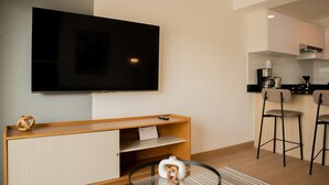A modern living room with a flat-screen TV, wooden entertainment unit, and a glass coffee table. - w Enchanting 1BR w Balcony in Barranco (Lima)