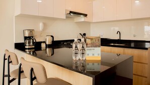 A modern kitchen with a central island, a coffee maker, two bottles of water, and a sign for 'Descubre Perú'. - w Enchanting 1BR w Balcony in Barranco (Lima)