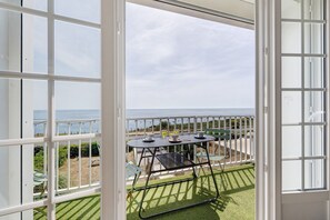 Ein Balkon mit Tisch und Stühlen, Blick auf das Meer und eine weiße Umzäunung.