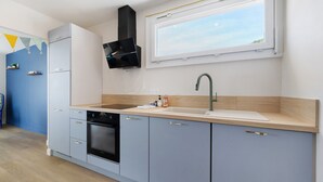 A modern kitchen with a built-in oven, a sink, and a window above the countertop. - Holiday Home “Les Sables Pailletés 14p” with Sea View, Shared Terrace & Wi-Fi (Les Sables-d'Olonne)