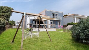 Una casa con un columpio, una hamaca y un césped bien cuidado.