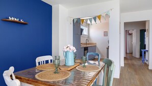 Un comedor con una mesa de madera, sillas blancas y una pared azul.