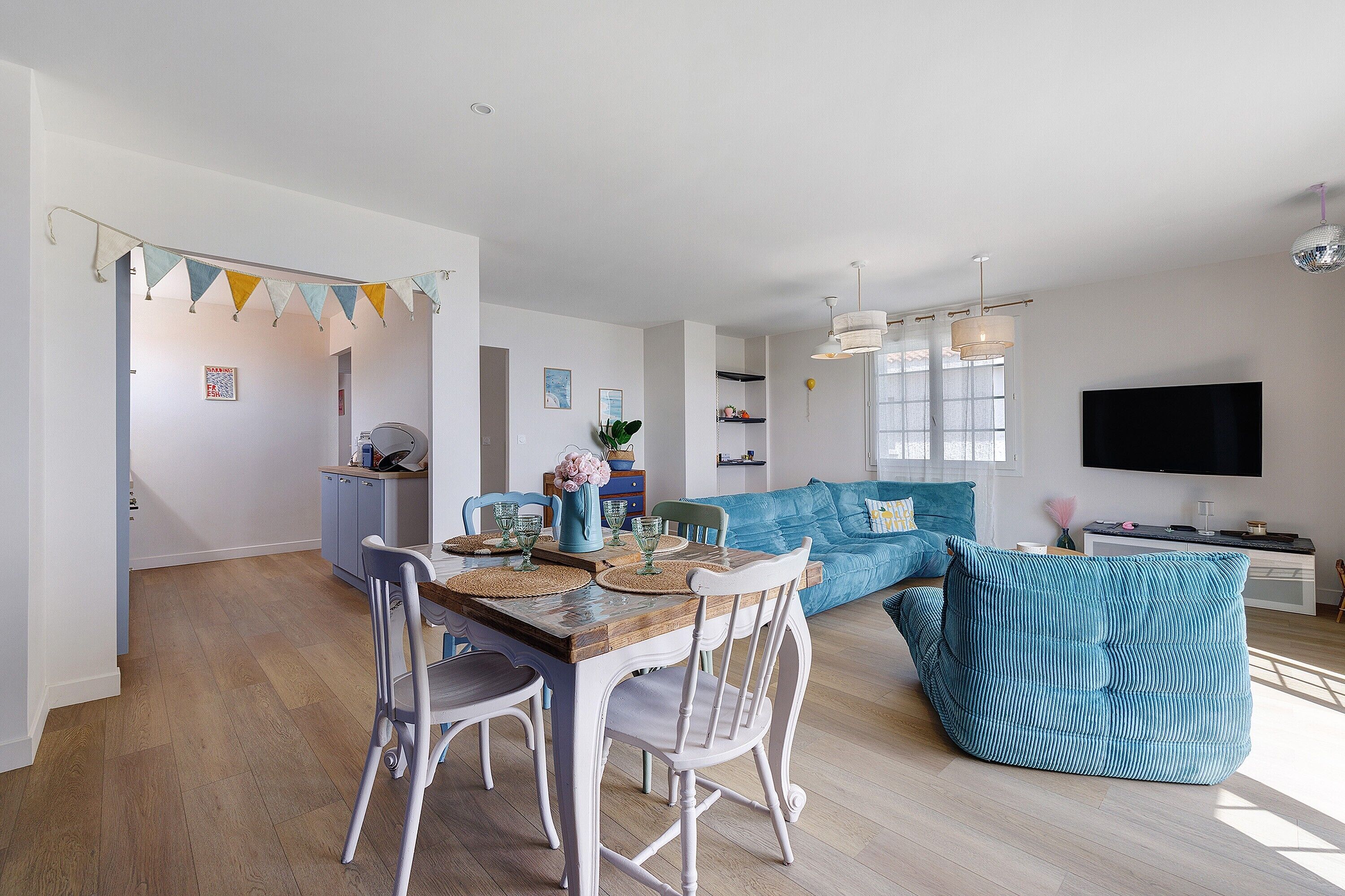 A modern living space with a dining area, a sofa, and a television.