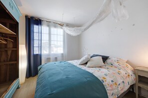 Ein Schlafzimmer mit einem Bett, einem Kleiderschrank, einem Fenster mit Vorhängen und einem Nachttisch.