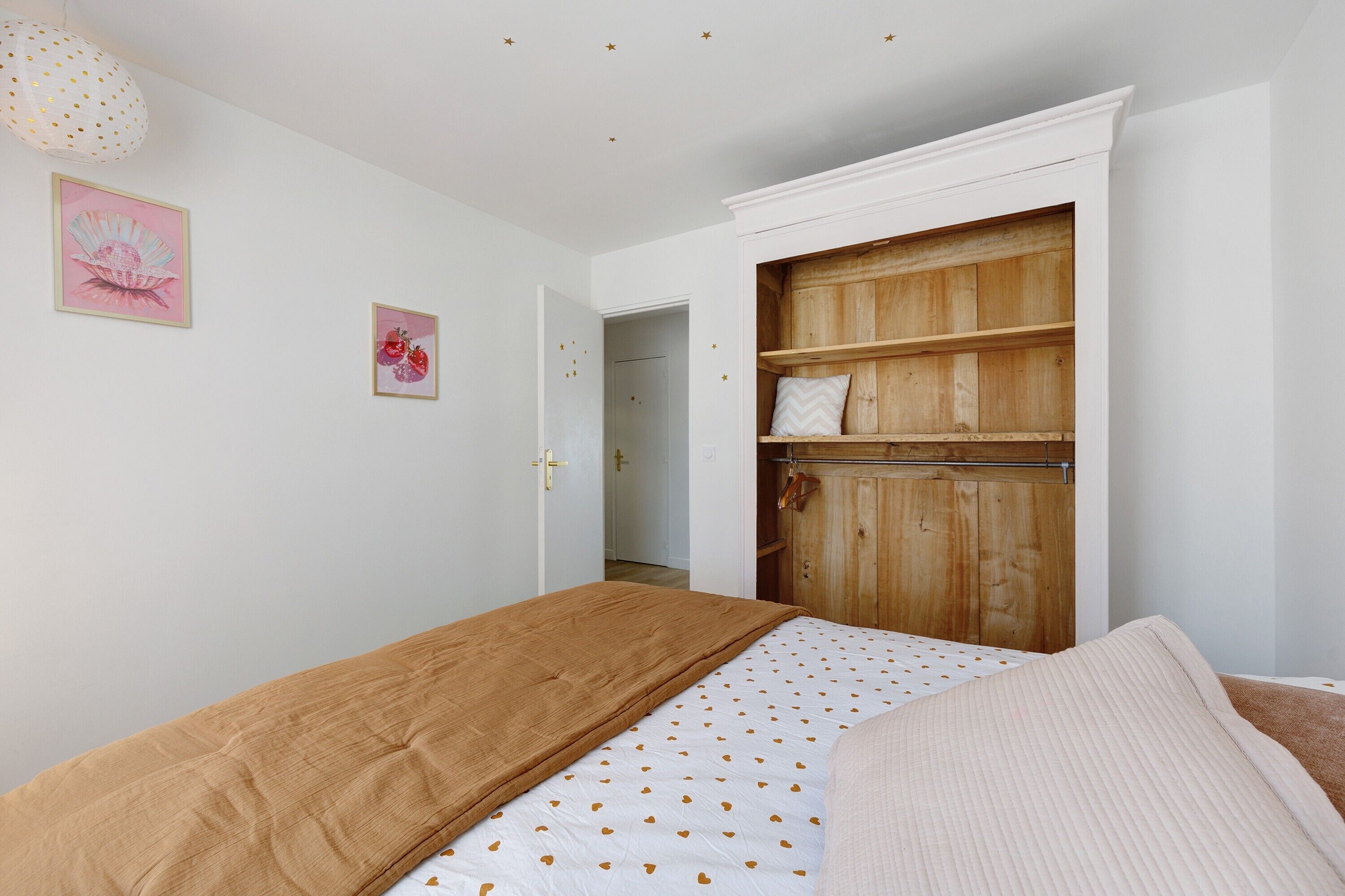 A bedroom with a bed, a wardrobe, and two framed pictures on the wall.