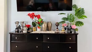 A black dresser with multiple drawers and a flat-screen TV mounted on the wall above it. - 3-bedroom house in Miami with large yard, jacuzzi and mango tree’s. (Miami)