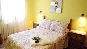 A bedroom with a large bed, two bedside tables, a nightstand, a ceiling light fixture, a wall-mounted artwork, and a window with curtains. - Rural Apartments La Viña (Apartment number 6) (Cangas de Onis)