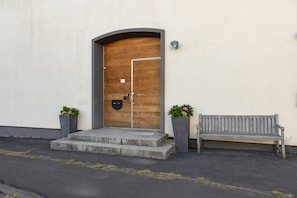 A wooden door with a metal handle, a mailbox, and a bench outside a building.