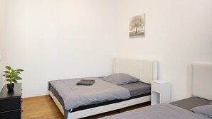 A bedroom with a single bed, a bedside table, a nightstand, a wall-mounted lamp, and a small potted plant. - Apartment '2' with Wi-Fi (Bad Kissingen)