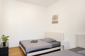 Ein Schlafzimmer mit einem Einzelbett, einem Nachttisch, einer Wandlampe und einem kleinen Topfpflanzen.