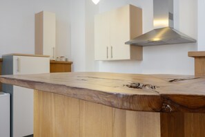 A kitchen with a wooden island, white cabinets, and a stainless steel range hood.