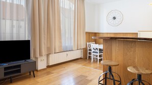 A modern living room with a flat-screen TV, a wooden dining table, and two bar stools. - Apartment '2' with Wi-Fi (Bad Kissingen)