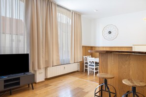Ein modernes Wohnzimmer mit einem Flachbildfernseher, einem Holzessttisch und zwei Barhocker.