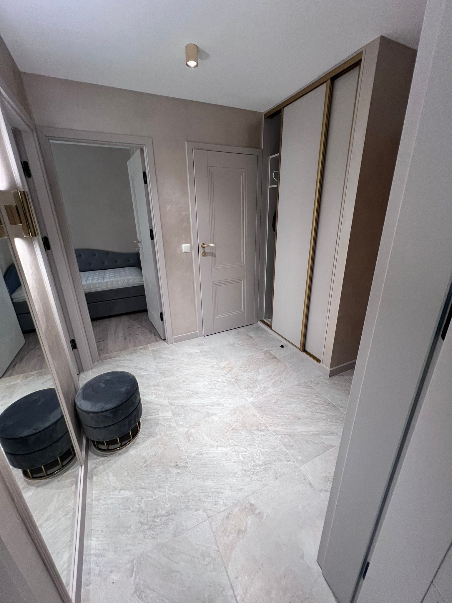 A bedroom with a bed, a wardrobe, and a small stool.