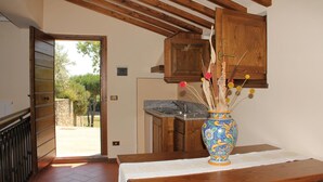 Une cuisine avec des meubles de rangement en bois, un évier et un vase contenant des fleurs séchées, posé sur une table.